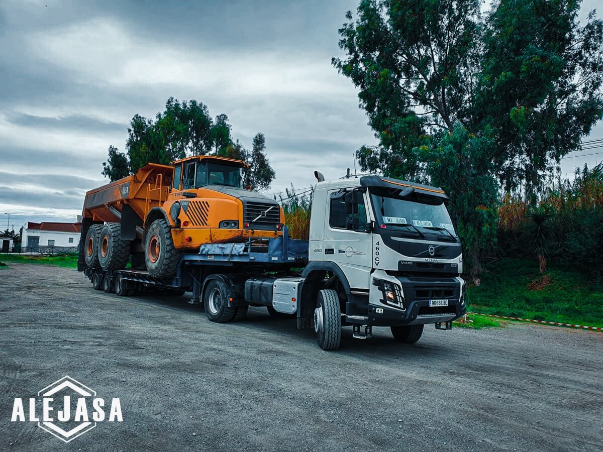 Camión con remolque de góndola transportando maquinaria